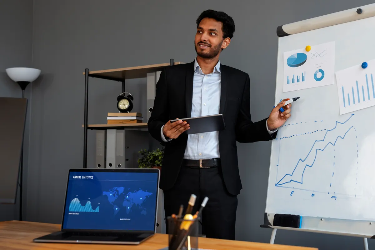 Business professional holding a tablet and presenting financial graphs on a flip chart.